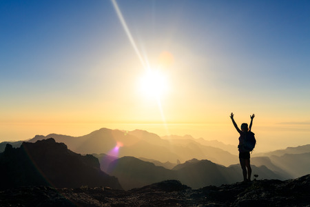 Woman hiking silhouette in mountains, sunset and ocean. Female hiker with arms outstretched on mountain top looking at beautiful night sunset inspirational landscape.の写真素材