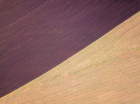 Aerial photo of a ploughed field in a countryside. Plowing in autumn season, drone shot from above.