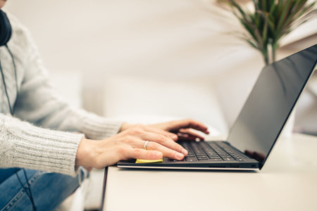 Woman working from home on laptop computer. Home office from a warm couch. Looking at screen. Focus...