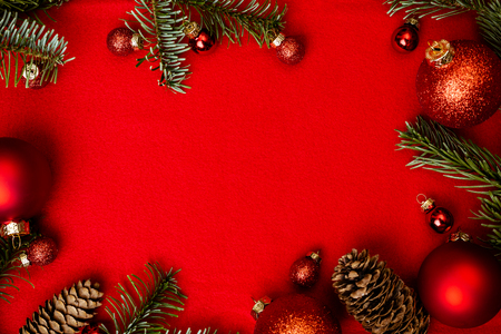 Christmas red background with fir tree, red christmass balls frame. Top flat view with copy space.の写真素材