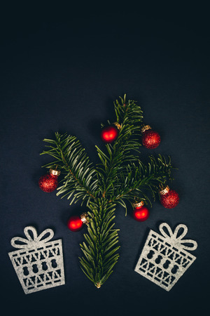 Christmas tree and gifts symbols over black background with fir tree, red christmas balls, top view. Flat inspiring holidays layout.の写真素材