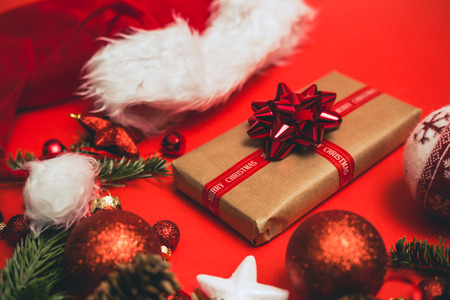 Christmas gift or present over red holidays background with fir tree and red christmas balls.の写真素材
