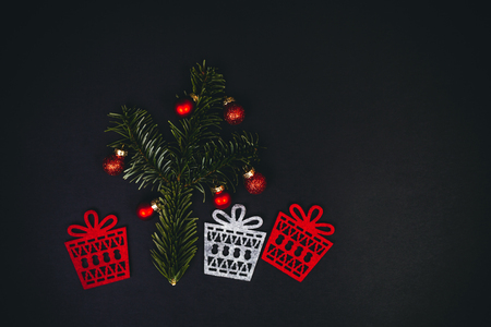 Christmas tree and gifts symbols over black background with fir tree, red christmas balls, top view. Flat inspiring holidays layout.の写真素材