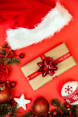 Christmas gift or present over red holidays background with fir tree and red christmas balls.の写真素材