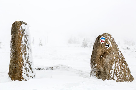 Hiking arrow signs on stone in deep snow, winter inspiring landscape. Beautiful inspirational scene with copy space.の写真素材