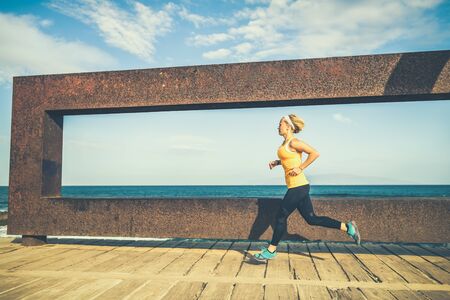 Young woman running in mountains on sunny summer day. Female runner exercising outdoors in nature, sunset.の写真素材