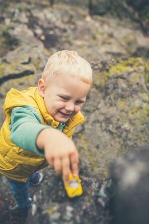 Toddler boy playing with toys on a rock. Little child walking on rocky mountains.の写真素材