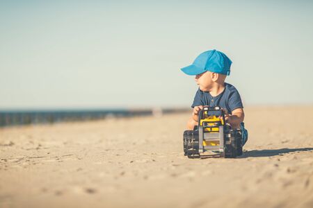 Toddler boy playing with toys on a sunny beach. Little child walking on sand. Beautiful inspirational beach and ocean view, landscape.の写真素材