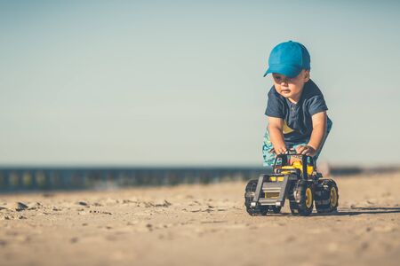 Toddler boy playing with toys on a sunny beach. Little child walking on sand. Beautiful inspirational beach and ocean view, landscape.の写真素材