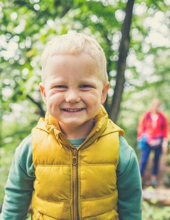 Toddler boy hiking with mother, family adventure. Little child walking in rocky green forest, smiling.の写真素材