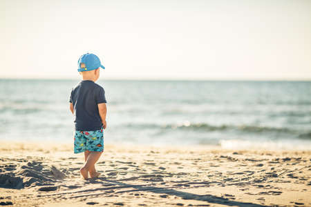 Toddler boy walking on a sunny beach. Little child walking on sand. Beautiful inspirational beach and ocean view, landscape.の写真素材