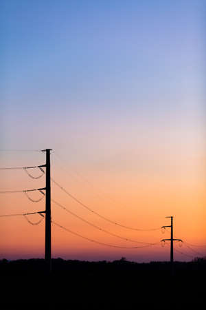 Silhouette of power lines over colorful clear sky at sunrise or sunset, blackout concept.の写真素材