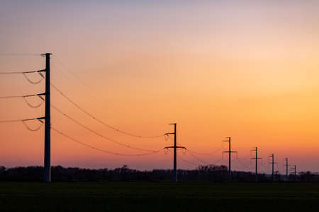 Blackout - silhouette of power lines over colorful clear sky at sunrise or sunset.の写真素材