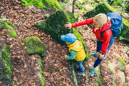 Little boy hiking with mother, family adventure. Child walking in rocky green forest, physical activity.の写真素材