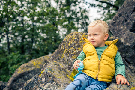 Little boy hiking in mountins, family adventure. Little child walking in rocky green forest, smiling.の写真素材