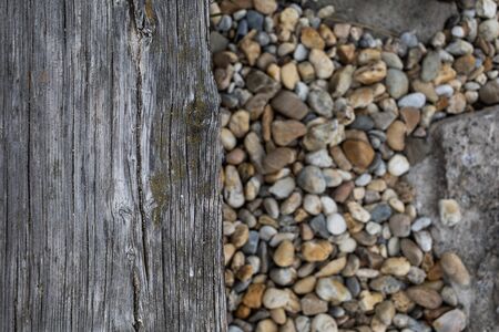 horizontal photo of an old board washed by waves and round stones overhead for background.の写真素材
