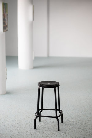 black bar stool in empty room in front of white wall