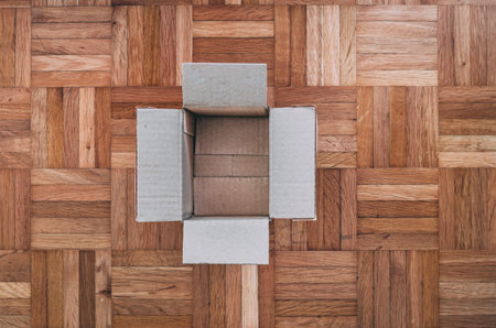 Empty cardboard box on a wooden tile floor, top viewの写真素材