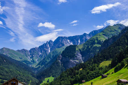 Swiss mountain landscape green grass, blue sky, white clouds, summer dayの写真素材