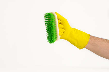 Male arm in yellow latex glove with coloured scrubbing brushの写真素材