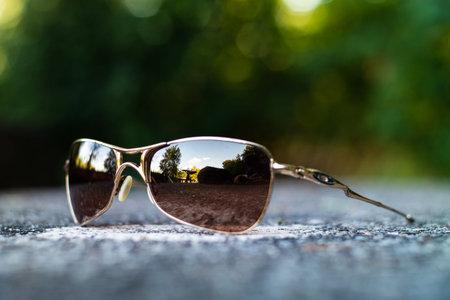 Orange frame and lens pair of sunglasses set on a concrete table in a park close up shallow depth of...