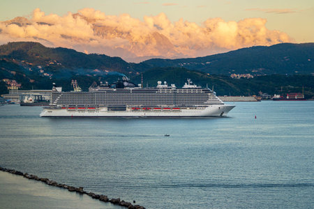 Giant cruise ship leaving the port of La Spezia Ligura Italy with the mountains in the background...