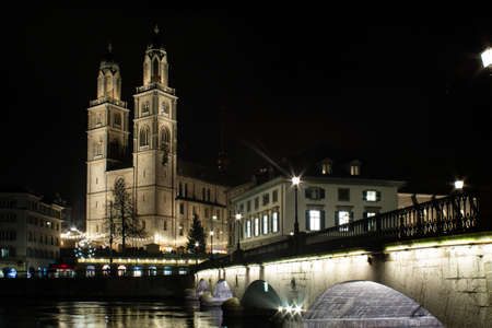 Grossmunster protestant church illuminated at night in Zurich  photographed from across the Limmat river with the old bridge visible on the right 2019の写真素材