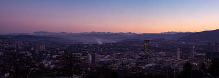 Beautiful panoramic vista view at dusk of Zurich city Switzerland from high vantage point in late autumn after sunset blue hour clear sky lake visible in the distance 2020の写真素材