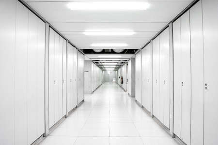 industrial building science laboratory empty corridor hallway illuminated by neon lights with locker doors across both sides 2020の写真素材