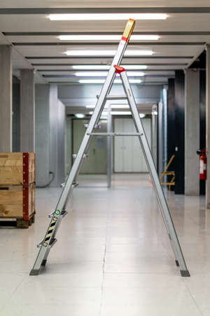 V shaped open ladder standing on a laboratory hallway corridor illuminated by neon lights shallow depth of field side view 2020の写真素材