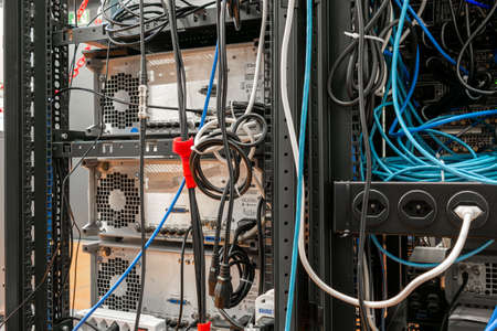 Convoluted mess of power sockets and tangled electrical cables tied together with zip ties hanging in a rack of electronic equipment in a scientific laboratory 2020の写真素材