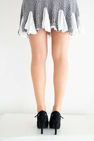 Young Caucasian female legs in stockings, short skirt and black shoes posing isolated against light background 2020の写真素材