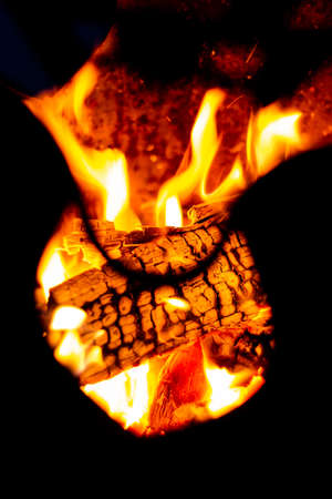Burning wood and open flames seen through the cutout part of a metal fire pit.の写真素材
