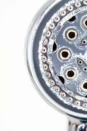 Silver round shower head with hard water deposit all around the sprinklers close up macro side shot isolated against white backdropの写真素材