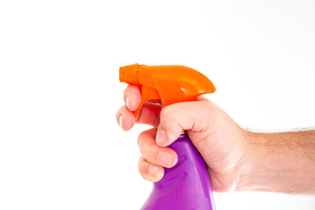 Colored liquid pulverizer held by Caucasian male hand close up shot isolated against white 2020