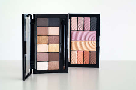 Two sets of cosmetic makeup powder various shades, colors and a brush isolated against white top viewの写真素材