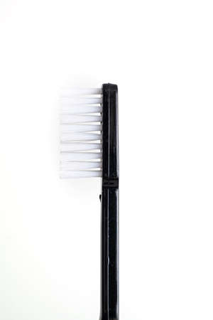 Simple new toothbrush with black plastic handle side view isolated on white background close up macro 2020の写真素材