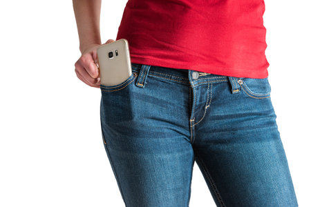 Young Caucasian female red t-shirt modeling smart phone in blue jeans pocket no face isolated on white 2020の写真素材