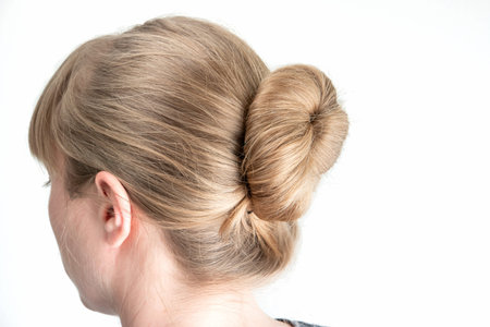 Simple bun hairstyle modeled by young white woman seen from behind close up shot isolated on white...