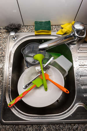 Kitchen sink full of dirty dishes cleaning sponge wire mesh and utensils top view 2020の写真素材