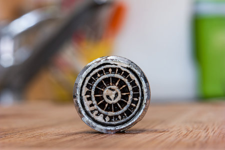 Old clogged up leaking faucet aerator with stone sand and Calcium sediment from hard water close up...