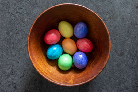 Colorful painted Easter Eggs in a brown wooden bowl shot in window daylight 2020の写真素材