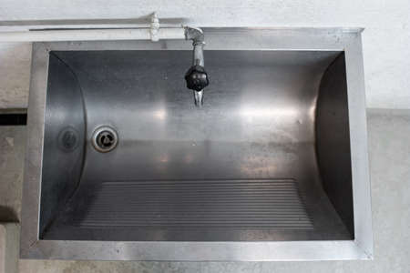 Large silver metal washing sink and piping inside a common use laundry room inside shot top view 2020の写真素材