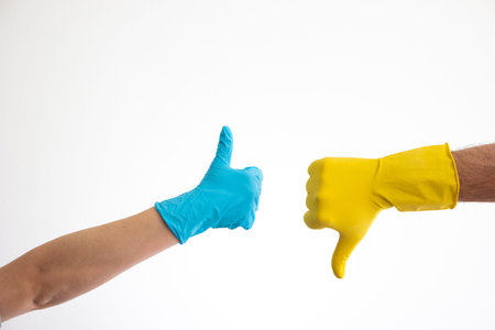 Caucasian woman and man hand in blue and yellow latex gloves doing the thumb up and down signs...