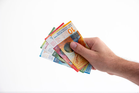 Caucasian adult male hand holding 4 Swiss currency francs cash bank notes isolated on white 2020