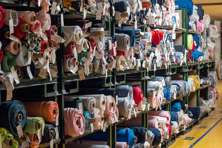 Big rolls of colorful fabric stacked on factory shelves ready for production.の写真素材