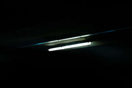 Dim blue neon light on the wall of a parking lot dark theme.の写真素材