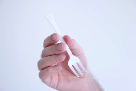 White plastic disposable fork modeled by Caucasian male hand isolated on white.の写真素材
