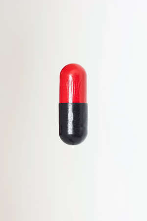 Red and black medicament capsule pill close up macro shot isolated on white.の写真素材