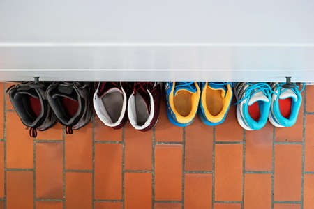 Row of used shoes lined up partially under shoe cabinet inside apartment top view.の写真素材